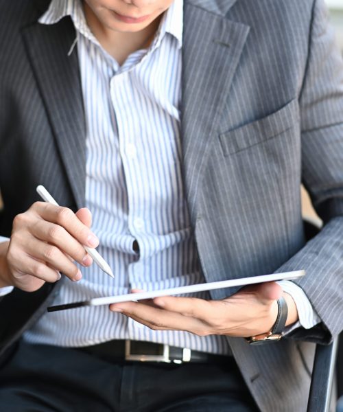 Cropped shot of businessman sitting on comfortable chair and using smart phone.