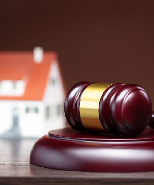 judge gavel on wooden table with house on backstage